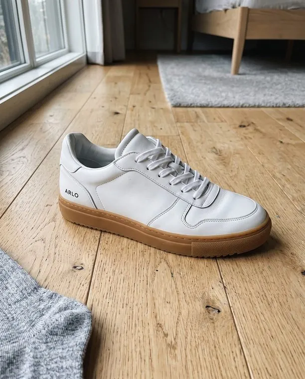 Das Original: ein Handyfoto eines weißen Sneakers auf einem Holzboden.